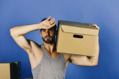 Mavi arka planda ağır kartonlu ve yorgun görünen adam.