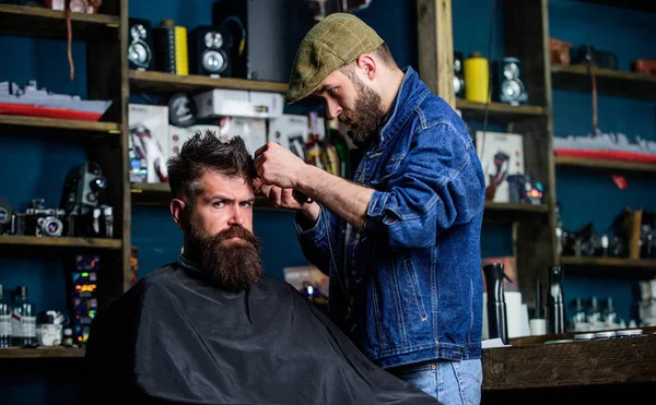 Hipster client getting haircut. Barber with hair clipper works on hairstyle for bearded man barbershop background. Hipster lifestyle concept. Barber with clipper trimming hair on temple of client — Stock Photo, Image