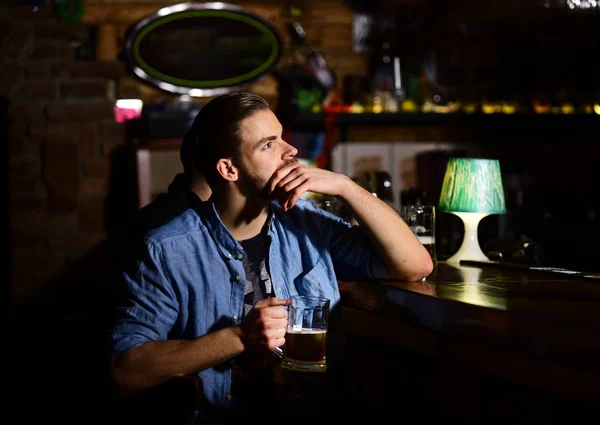 Guy sentado no balcão do bar e bebe cerveja . — Fotografia de Stock