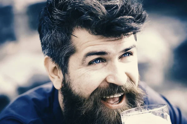 Happy bearded man with long beard enjoying a glass of beer, Friday night out. Closeup cheerful man with blue eyes and messy hairstyle looking up