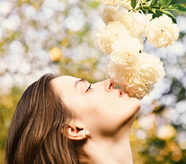 Chica mira a las flores en el fondo de la naturaleza, desenfocado . —  Fotos de Stock