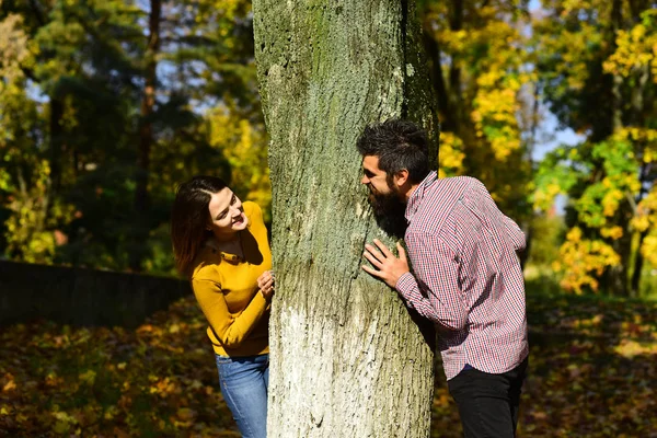 Verliefde paar speelt achter de boom in herfst park. — Stockfoto