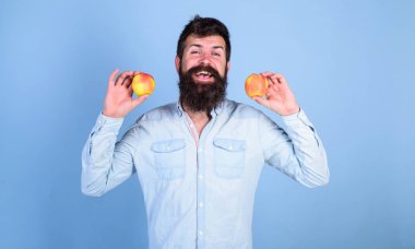 Sağlıklı bir alternatif. Sakallı adam gülen elma mavi arka plan elinde tutar. Elma hem de sağlıklı alternatif eller. Tamamen sağlıklı beslenme kavramı. Vitamini beslenme diyet sağlık