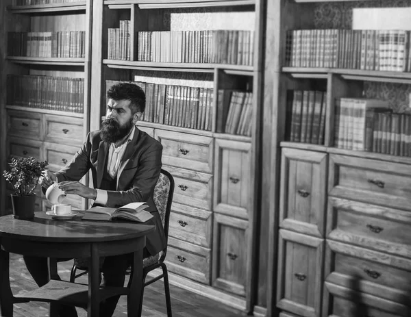 Man in classic suit sits in vintage interior, library