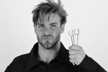 Katı yüzlü bir adam İngiliz anahtarlarını beyaz arka planda tutar.