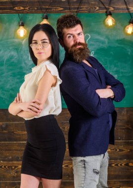 Sakal ve gözlük stand sırt sırta, kara tahta arka plan öğretmen olan adam. Okul personeli kavramı. Bayan ve birlikte okulda çalışan hippi. Öğretmen ve öğretmen rahat görünüyor