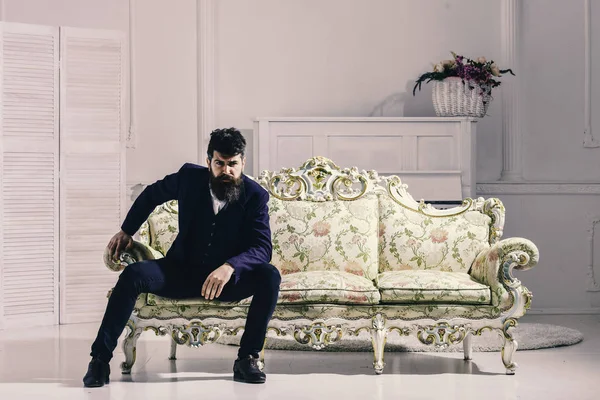 Maço çekici ve zarif ciddi bir yüz ve düşünceli ifade. Adam sakal ve bıyık moda klasik takım elbise ile eski moda koltuk ya da kanepe üzerinde oturur. Moda ve stil kavramı