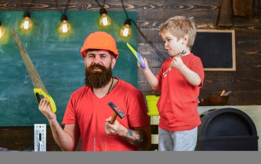 Babalık kavramı. Baba, üst koruyucu kask okul atölyesinde farklı araçları kullanmak için küçük oğlu öğretim içinde sakallı. Çocuk, çocuk neşeli oyun ve babamla araçları kullanmayı öğrenme