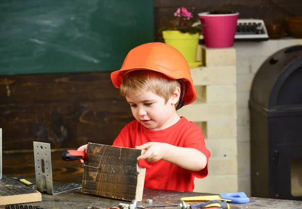 Kid boy in orange hard hat or helmet, study room background. Childhood concept. Child dreaming about future career in architecture or building. Boy play as builder or repairer, work with tools — Stock Photo, Image