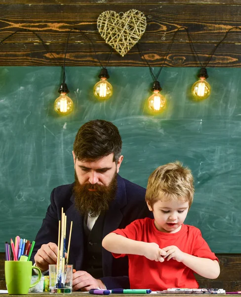 Yetenek ve yaratıcılık kavramı. Çocuk ve resim, çizim meşgul yüzleri öğretmen. Sakal, baba ve küçük oğul çizerken, sınıfta oluşturma, kara tahta arka plan ile öğretmen