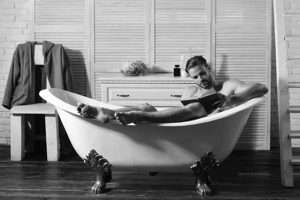 Sakallı ve odaklanmış yüz okuma kitabı olan bir adam.