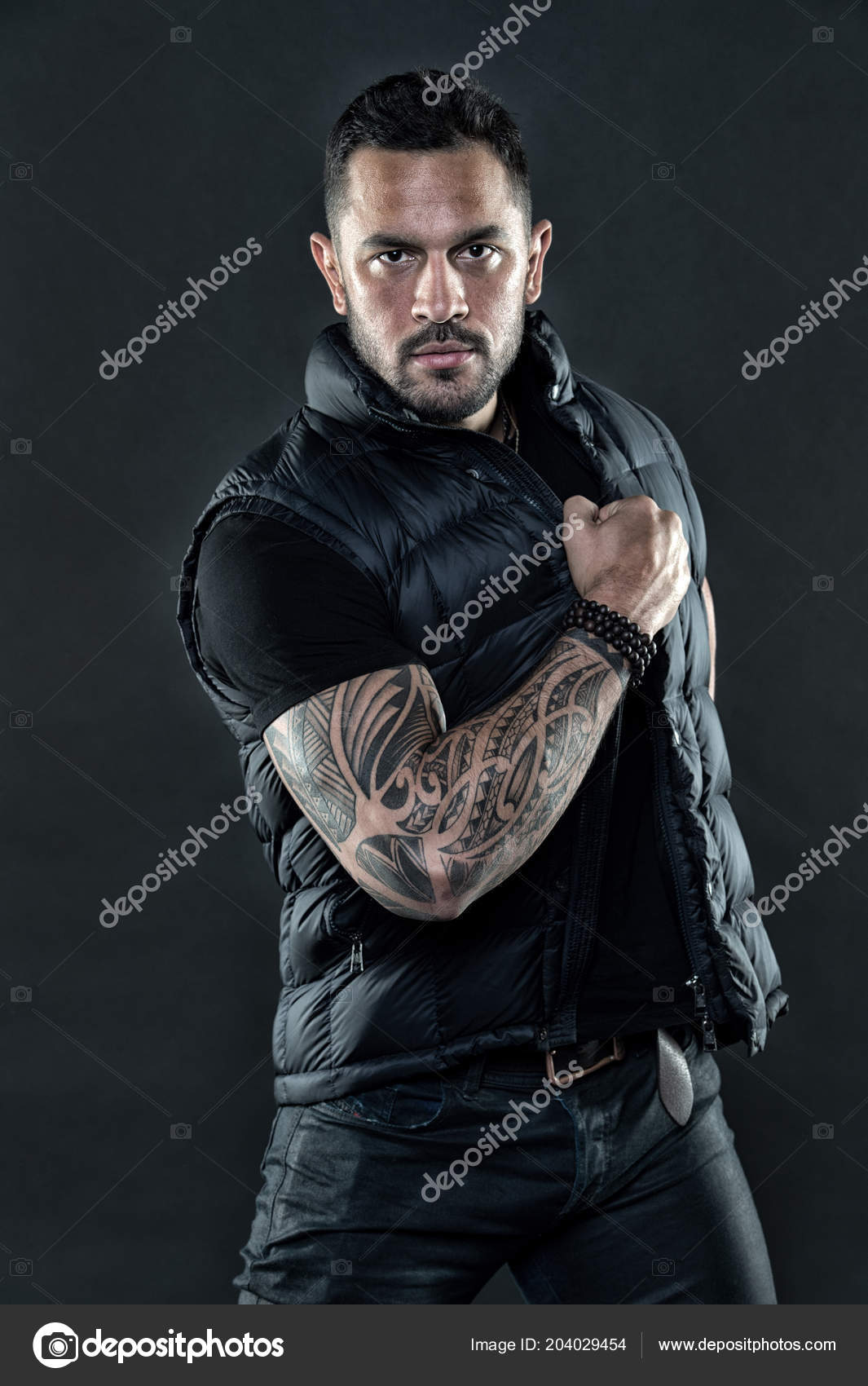 Tatovert mann i trendy klær. Mann med tatovering på hud med sterk arm. Mote  macho med selvtillit og karisma. Tatoveringsmodell med skjegg på ubarbert  ansikt. Motestil og trend, årgangsfilter – stockfoto ©, image size:1065x1700