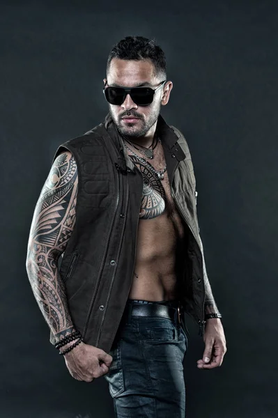 Tattooed man with six pack and ab. Bearded man with tattoo on chest and arms. Tattoo model with beard on unshaven face. Fashion style and trend. Fashion macho in trendy sunglasses, vintage filter
