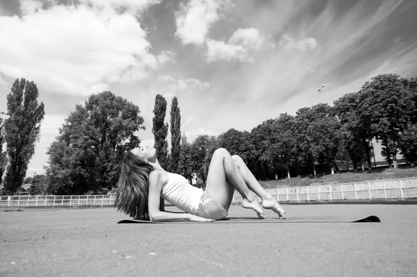 Frau macht Pilates auf Yogamatte. sinnliche Frau entspannen im Stadion. Modeathleten praktizieren Yoga im Freien. Wellness und Körperpflege. Sport oder Fitness- und Pilates-Konzept — Stockfoto