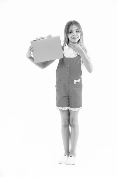 Little child point finger at shopping bag isolated on white. Happy girl smile with paper bag. Kid shopper in fashion jumpsuit. Holidays and celebration. Shopping at black friday. All I got on sale. — Stock Photo, Image