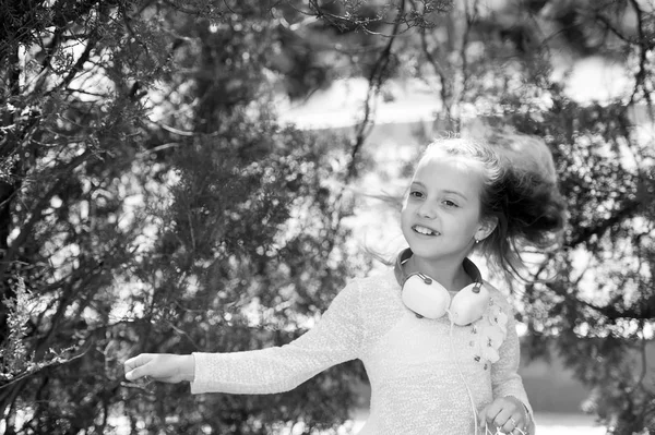 Дівчина танцює музику в літньому парку. Дитяча танцівниця з довгим літаючим волоссям. Маленька дитина насолоджується музикою на відкритих навушниках. Звук мелодії та mp3. Літо весело і радісно — стокове фото