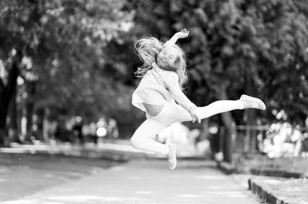 Gelukkig meisje sprong hoog in de zomer park. Klein kind glimlach met vliegende haar in beweging vrij gevoel. Mode kind veel plezier buiten. Vrijheid en energie. gevoel van vrijheid. Jeugd activiteit en actieve spelletjes — Stockfoto