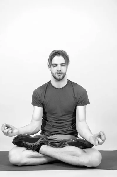 El hombre medita en la esterilla de yoga. Deportista relajarse en la pose de loto. Atleta de moda practica yoga en el gimnasio. Meditación para la salud del cuerpo y la mente. Meditación o zen y concepto de paz — Foto de Stock