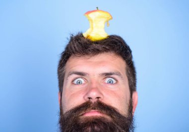 Hipster şok ile elma güdük hedef üzerinde kafa mavi arka plan, yüz kadar yakın. Kilo kaybı gol. Canlı hedef kavramı. Adam yakışıklı hipster uzun sakal neredeyse kafasına elma güdük hedef olarak yem.
