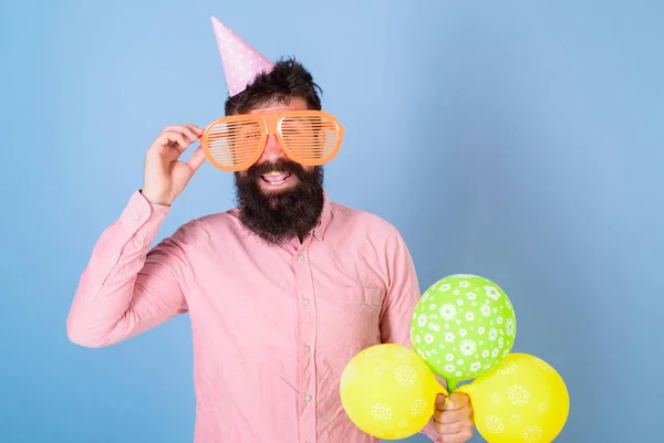 Glücklicher bärtiger Mann mit riesiger Brille, der mit bunten Luftballons posiert, lustiges Konzept. Komiker mit verrücktem Aussehen unterhält die Gäste bei besonderen Veranstaltungen. Performer mit wildem Bart bei Geburtstagsparty — Stockfoto