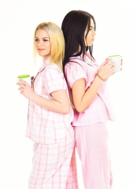 Pijama ile bir bardak kahve, beyaz bir arka plan üzerinde izole neşeli kızlar. Sabah kahve kavramı. Kız arka arkaya stand ve kahve içmek