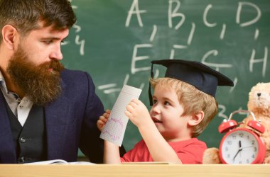 Öğretmen, babası ödev, kontrol yardımcı olur çocuk için evlat. Bireysel eğitim kavramı. Öğretmen formal giyim ve öğrenci sınıfta kolej, kara tahta arka plan. Meşgul çocuk okulda eğitim