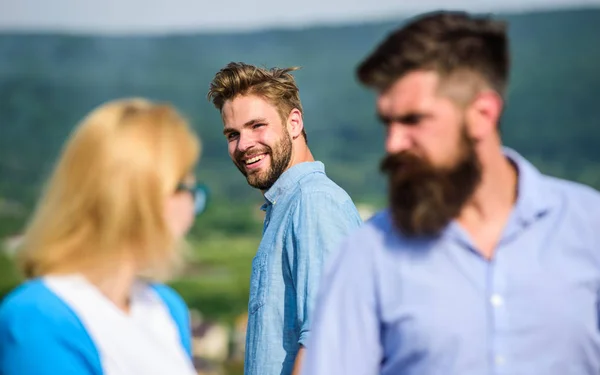 Man with beard jealous aggressive because girlfriend interested in handsome passerby. Jealous concept. Passerby smiling to lady. Husband strictly watching his wife looking at another guy while walk.