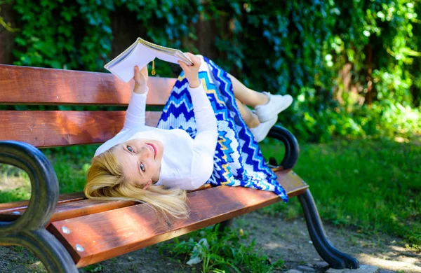 Girl lay bench park relaxing with book, green nature background. Woman spend leisure with book. Girl reading outdoors while relaxing on bench. Time for self improvement. Lady happy face enjoy reading — Stock Photo, Image