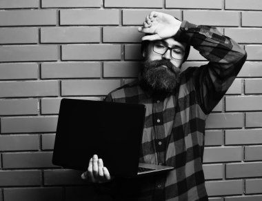 Kaba sakallı, beyaz tenli hippi dizüstü bilgisayar tutuyor.