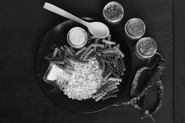 Italian dish placed on dark wooden table. Jars of spices — Stock Photo, Image