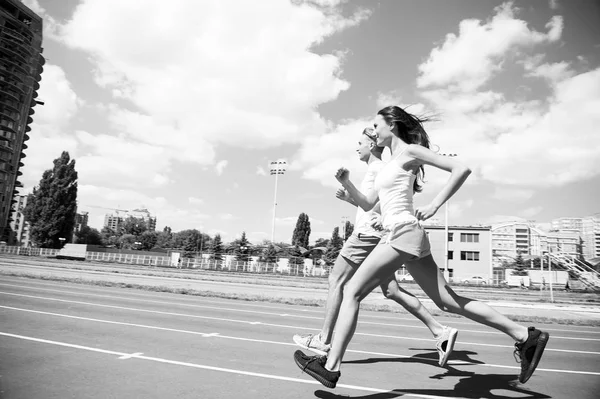 Un par de corredores soleados al aire libre. Mujer y hombre corren en el estadio. Actividad y energía. Entrenamiento y entrenamiento al aire libre. Salud y bienestar deportivo — Foto de Stock