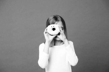 Tatlı ruh hali. Çocuk çörek mor zemin üzerine bak. Sırlı halka halka mor zemin üzerine olan küçük kız. Abur cubur ile evlat. Yemek ve tatlı. Çocukluk ve çocuk bakımı, kopya alanı