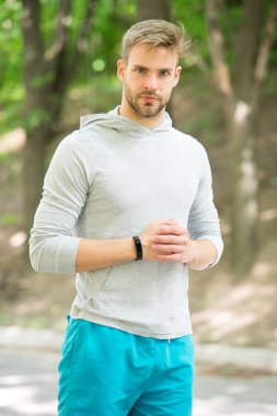 Önünüze çıkan her engeli aşmak hazır. Sporcu pedometre gadget ile eğitim. Adam atlet sıkı yüz spor ekipmanları doğa arka plan ile. Atlet fitness izci veya pedometre egzersiz için hazır