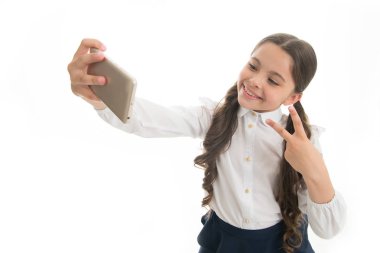 Genç vlogger akışı çevrimiçi. Çocuk okulu üniforması zeki çocuk gülen surat. Şirin, uzun kıvırcık saçlı bir kız akıllı telefon tutuyor ve selfie beyaz arka plan çekiyor. Çocuk okulu üniformaları akıllı telefon bulundurur.