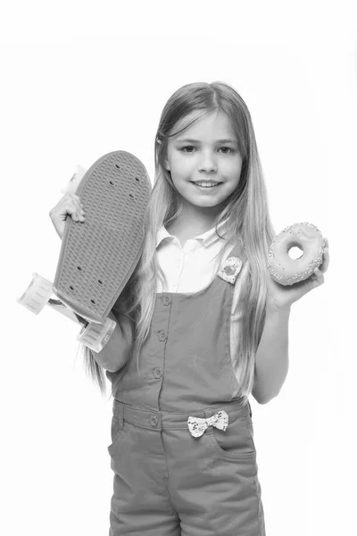 スケート ボードと白で隔離ドーナツ少女の笑顔。ドーナツとロングボード子供スケーター。ジャンク フードと子供のスケート ボード。スポーツとエネルギー。軽食やデザートのための食糧。ダイエットの概念 — ストック写真