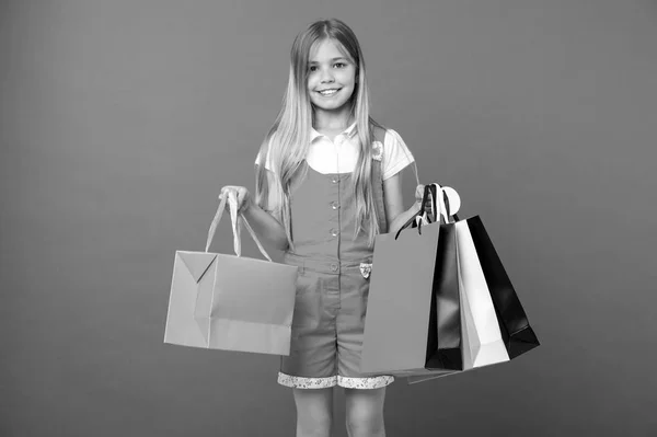 Niño feliz con bolsas de compras sobre fondo violeta. Sonríe con bolsas de papel. Comprador de niños en mono de moda. Preparación y celebración navideña. Después de ir de compras. venta y viernes negro —  Fotos de Stock