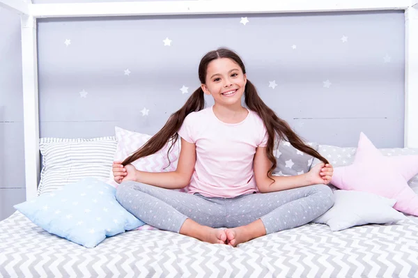 Relaxation and meditation. Girl child sit on bed in her bedroom. Kid prepare to go to bed. Pleasant time for evening meditation. Girl kid long hair cute pajamas relaxing and meditating in bedroom