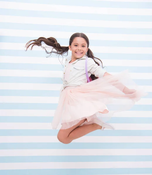 Lleno de energía. Chica cara feliz cola de caballo peinado salta en el aire. Niña vestido elegante salto lleno de energía. Su infancia llena de felicidad y alegría. Niña feliz se siente despreocupada y juguetona — Foto de Stock