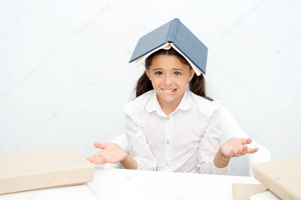 How is it possible to learn. Girl child confused exhausted with book roof on head white background. Schoolgirl tired of studying and reading. Kid school uniform tired face not want continue reading