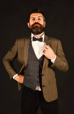 Eskimiş şık takım elbiseli ve kahverengi arka planda yelek giyen adam.