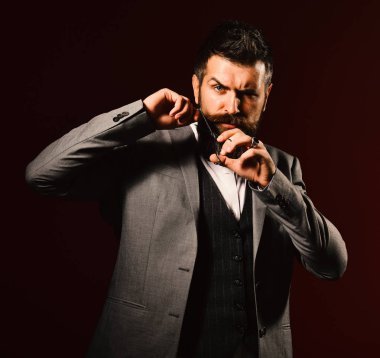 Koyu kırmızı arka planda kafası karışmış bir iş adamı.