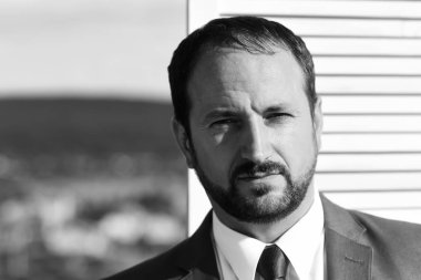İşadamı ahşap duvara şık bir takım elbise ve kravat takar.
