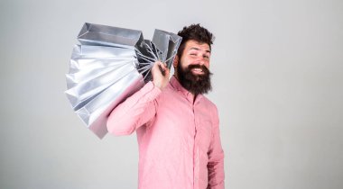 Hippi üzerinde yüz alışveriş göz kırpıyor. Adam alışveriş satış sezonu üzerinde omuz grup taşır. Sakal ve bıyık tutan alışveriş torbaları, gri arka planı olan adam. Alışveriş kavramı