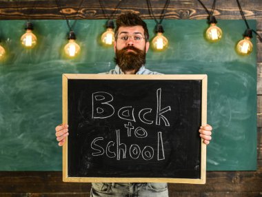 Lise kavramı. Adam sakal ve bıyık sakin yüz memnuniyetle öğrencilerin, kara tahta arka plan ile. Gözlük öğretmen okul için başlıklı yazı tahtası tutar