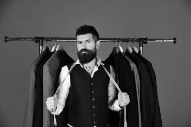 Elbise rafında sakallı bir adam. Tasarımcı önlem alır