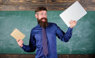 Öğretmen sakallı hippi kitap ve laptop tutar. Ne tercih ederim. Öğretmen modern öğretim yaklaşımı seçme. Kağıt kitap dizüstü karşı. Dijital kağıt karşı. Şu öğretim yöntemi seçin