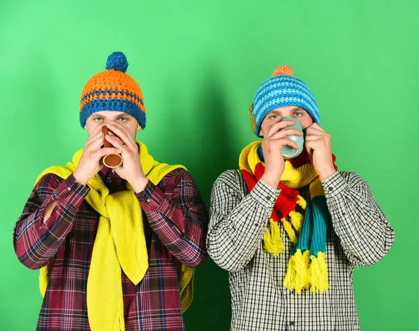 Twin brothers wearing warm hats and scarves hold cups — Stock Photo, Image