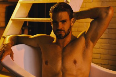 Romantik ışık banyo küvetinde çıplak olarak oturan maço