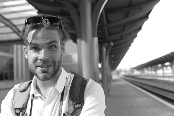 Guy with sunglasses waits for train, defocused.