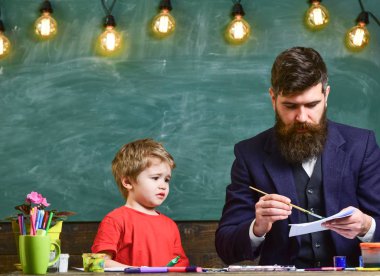 Çocuk ve meşgul yüz boyama, resim öğretmeni. Öğretmen sakallı, çizim arka plan kara tahta sınıf, küçük oğlu yakınındaki, takılmak iken Peder. Sanat ders kavramı